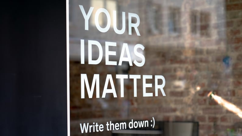 text on a glass door that says your ideas matter, write them down